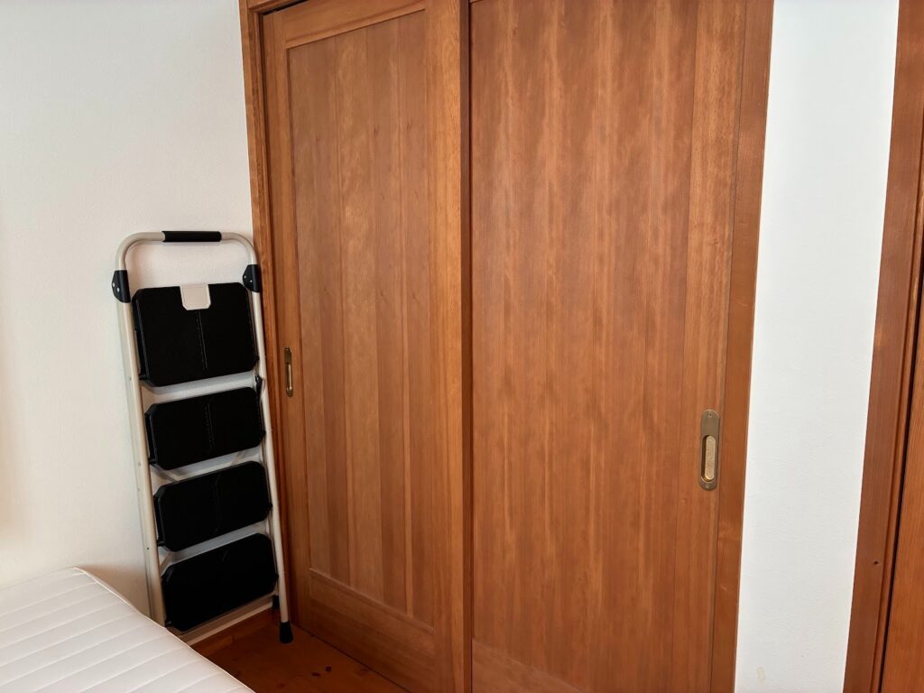 部屋の隅に折り畳んで立てかけてあるPYKES PEAK (パイクスピーク)の折りたたみ脚立の画像